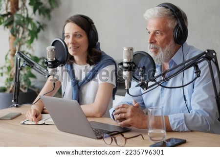 female and male podcasters record audio content in sound studio. social media, news program on radio. couple wearing headphones and microphones are having dialogue about business and creativity