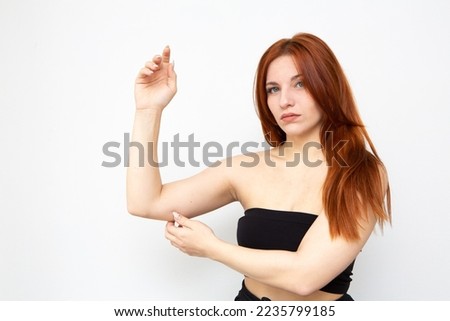 Woman pinching the skin beneath her arm to control fat and excess skin like bat wings or bingo wings Royalty-Free Stock Photo #2235799185