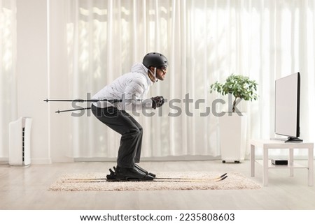 Profile shot of a man skiing at home in a living room in front of  tv















