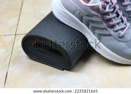 Grey Mattress and sport shoes on the floor. Indoor workout concept and healthy lifestyle. Sport equipment background.