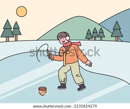 A boy wearing a hanbok in the cold winter is playing tops on the ice.