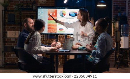 Company employee explaining analytics research results in business meeting, showing statistics data on digital board. Marketing revenue report presentation, colleagues team planning sales strategy