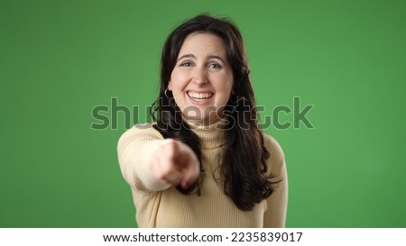 Young excited happy fun woman 20s look camera laugh smiling watch comedy movie pointing index finger on you isolated on green screen background studio portrait.