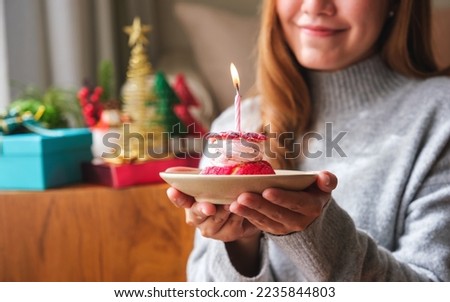 Closeup image of a young woman holding birthday cake with candle, Christmas holiday decoration at home