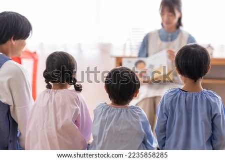 A nursery teacher reading to a kindergartener