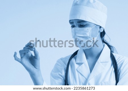 Doctor wearing face mask looking at measurement on medical thermometer over white background
