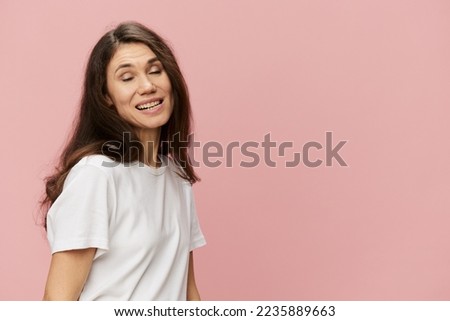 portrait of a funny strange woman with a wry smile and closed eyes standing in a white t-shirt