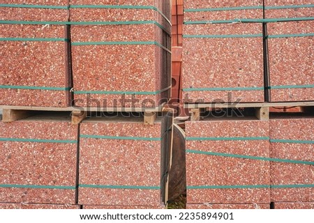 Red paving slabs on pallets in storage. Goods in stock, construction and repair, delivery and sale of building materials.
