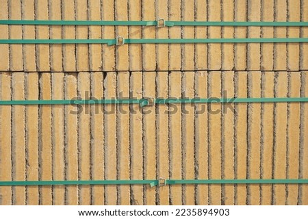Paving yellow road tiles packed with green tape on pallets in storage. Goods in stock, construction and repair, delivery and sale of building materials.