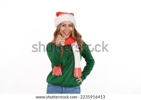 Attractive excited asian female in green sweater with santa hat on christmas isolated on white background. Pointing hand