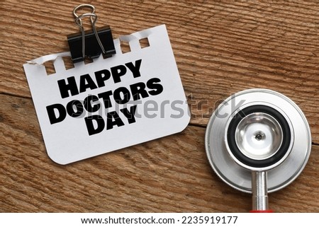HAPPY DOCTORS DAY words on a piece of paper next to a stethoscope.