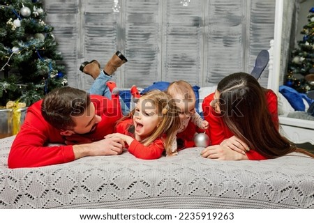 Young family on the bed with children on the background of the Christmas tree