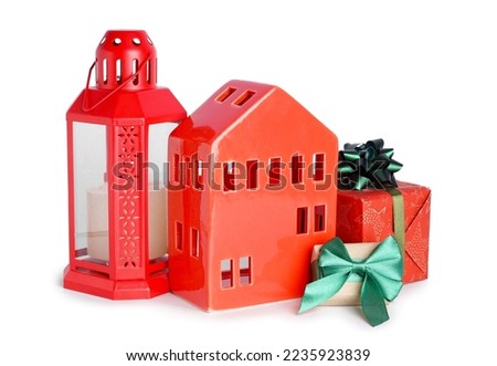 Candle holder in shape of house with Christmas lantern and gifts on white background