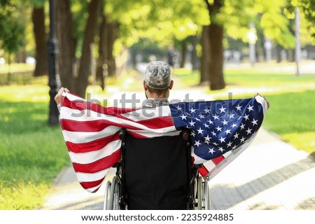 Young soldier in wheelchair with USA flag outdoors, back view