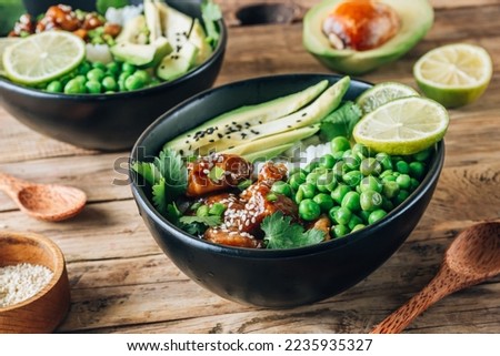 Buddha bowl with crispy sesame chicken asian style. Sweet and sour fried chicken with steamed rice, peas and acocado Royalty-Free Stock Photo #2235935327