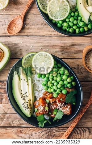 Buddha bowl with crispy sesame chicken asian style. Sweet and sour fried chicken with steamed rice, peas and acocado Royalty-Free Stock Photo #2235935329