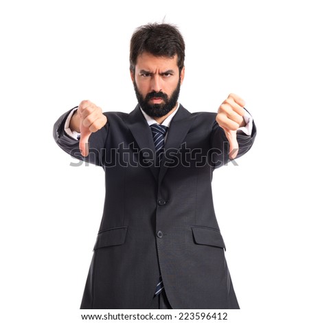 Businessman doing a bad signal over white background