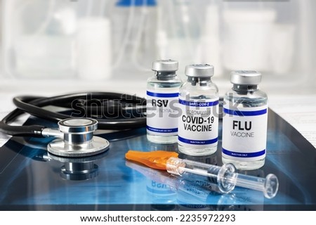Bottles of vaccine for Influenza Virus, Respiratory Syncytial virus and Covid-19 for vaccination. Flu, RSV and Sars-cov-2 Coronavirus vaccine vials over Radiography pulmonar with stethoscope Royalty-Free Stock Photo #2235972293