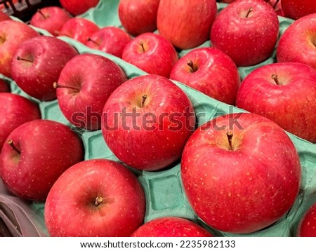 A bunch of ripe apples with red skin on the fruit shelf in the supermarket