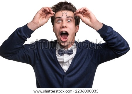 Astonished funny male nerd raising glasses and looking at camera with opened mouth against white background