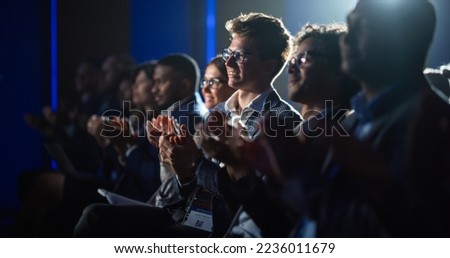 Young Male Sitting in a Crowded Audience at a Science Conference. Delegate Cheering and Applauding After an Inspirational Keynote Speech. Auditorium with Young Successful Specialist.