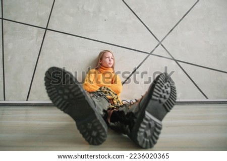stylized photo of a thoughtful girl sitting near a wall. Royalty-Free Stock Photo #2236020365