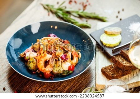 Warm salad with Argentinian king prawns. Almond potato, mini romaine lettuce, carrot, cherry tomato, pesto, black root chips, caramelized walnut, beet balsamic. Food served in modern restaurant. Royalty-Free Stock Photo #2236024587