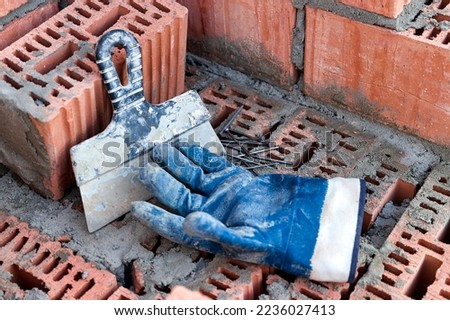 Construction tool for laying bricks and blocks. Bricklayer's tools - hammer, spatula, trowel, gloves. Hand tools on the background of brickwork Royalty-Free Stock Photo #2236027413