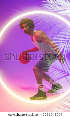 Side view of biracial male player dribbling basketball by illuminated plants and circle, copy space. Composite, sport, competition, illustration, glowing, nature and shape concept.