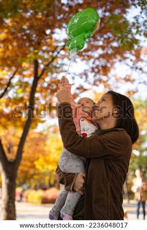 a mother and daughter very happily playing with the balloon in autumn season at Seoul Forest Park