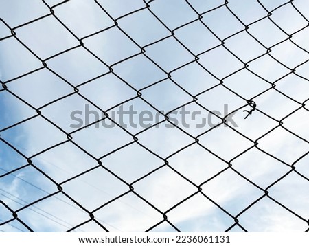 metal mesh fence. Grid net fencing wire against cloudy sky