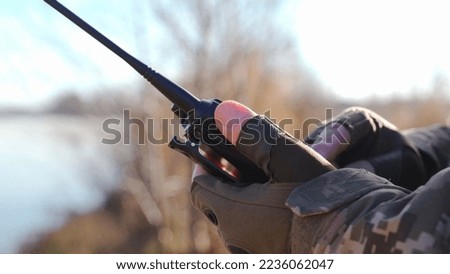 a military man in a camouflage uniform and tactical gloves adjusts a walkie-talkie to communicate with units Secure communication of the Ukrainian army during the war. encryption of radio broadcasts Royalty-Free Stock Photo #2236062047