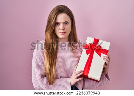 Young caucasian woman holding gift skeptic and nervous, frowning upset because of problem. negative person. 