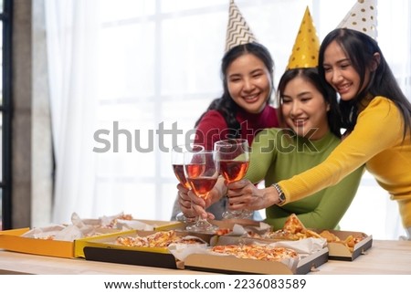 Group of happy young Asian people with friends celebrating clinking glasses during dinner party.