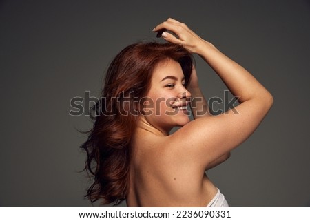 Portrait of young beautiful red-haired woman with natural, perfect skin isolated on dark grey background. Cosmetological care. Concept of beauty, cosmetology, hair treatment, cosmetics. Ad, poster