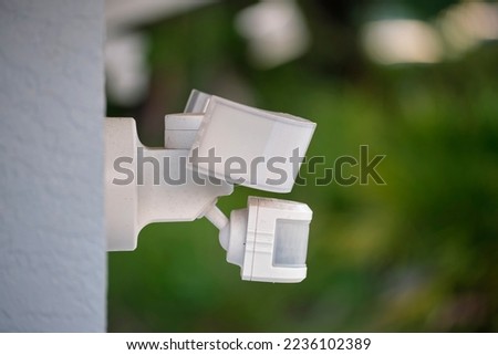 Motion sensor with light detector mounted on exterior wall of private house as part of security system Royalty-Free Stock Photo #2236102389