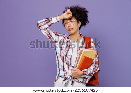 Young girl woman of African American ethnicity teen student in shirt backpack hold books put hand on forehead isolated on plain purple background. Education in high school university college concept