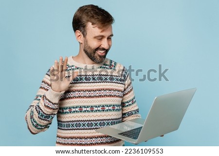 Young caucasian IT man 30s he wear sweater hold use work on laptop pc computer waving hand get video call isolated on plain pastel light blue cyan background studio portrait. People lifestyle concept Royalty-Free Stock Photo #2236109553
