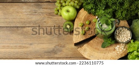 Mason jar of fresh green smoothie and ingredients on wooden table, flat lay. Space for text. Banner design