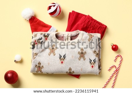 Set of childrens clothes for Christmas. Christmas sweater, pants, santa hat and decorations on a color background. New Year baby outfit, kids fashion concept.