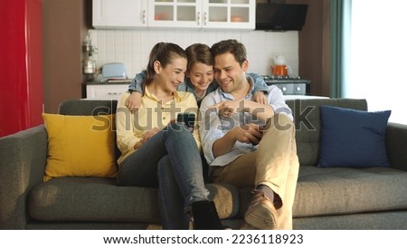Happy adult parents with cute kids looking at phone screen having fun with technology together. Technology addicted family having fun with smartphone.