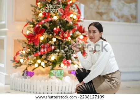 Asian woman​ in white sitting above Christmas tree, celebration, New year concept.​