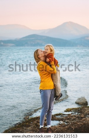 Mother kissing hugging daughter walking outdoor family lifestyle travel together summer vacations woman with child at the lake Mothers day holiday Royalty-Free Stock Photo #2236131513