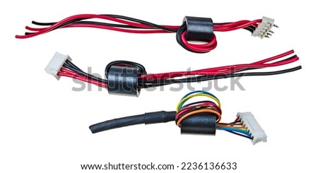 Ferrite bead inductors on insulated wires with plastic connectors isolated on a white background. Set of toroid core chokes as EMI fIlter to block unwanted high frequency noise in electronic circuits. Royalty-Free Stock Photo #2236136633