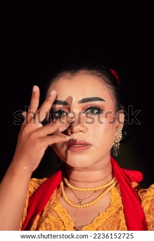 Gorgeous Asian woman wearing makeup and flowers in her hair while wearing a traditional orange dress and red scarf on her body at the night