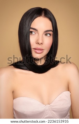 Portrait of beautiful young woman with healthy strong hair on beige background