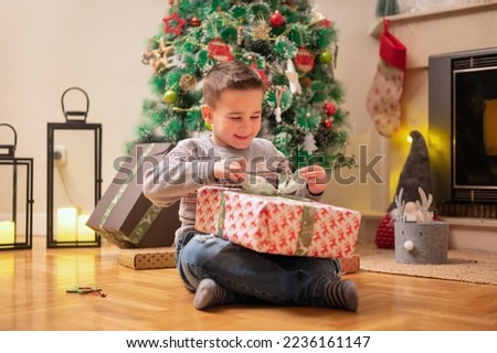 Boy opening christmas present. High quality photography.