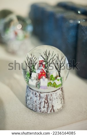Christmas snow globe with a small house and trees on the shelf of Xmas store or market or in  apartment interior as home decor