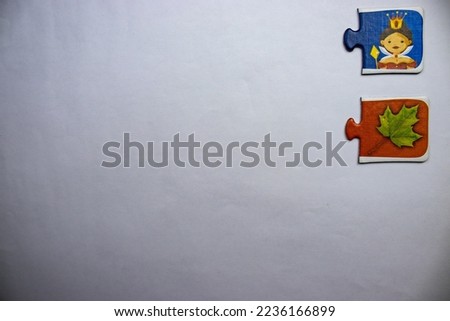 Puzzle pieces with a picture of a queen and a picture of a green leaf placed at the top right of a white background. Royalty-Free Stock Photo #2236166899