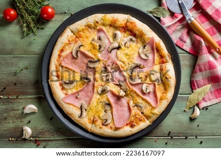 Pizza with ham and mushrooms on green wooden table top view